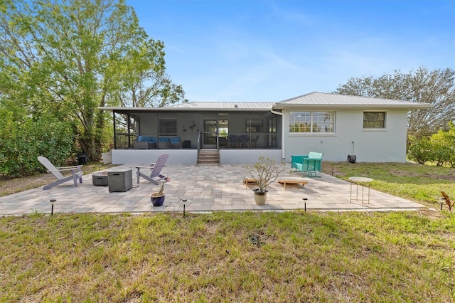 rear view of house featuring a fire pit, a sunroom, metal roof, a yard, and a patio area