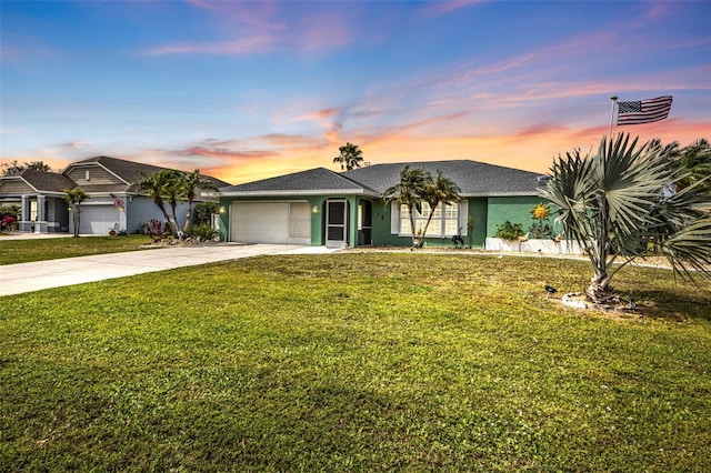 view of front of house with driveway, a yard, an attached garage, and stucco siding