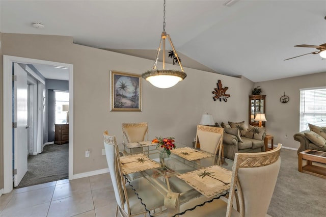 dining area with light carpet, light tile patterned floors, baseboards, a ceiling fan, and lofted ceiling