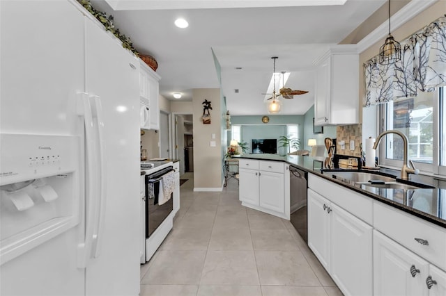 kitchen with white appliances, white cabinets, dark countertops, a peninsula, and a sink