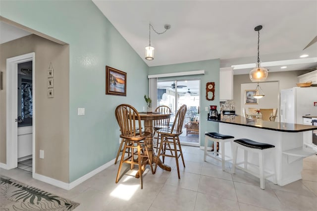 dining area with lofted ceiling, ceiling fan, baseboards, and light tile patterned flooring