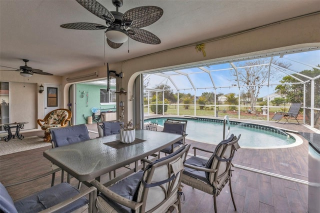 view of patio with a ceiling fan, a lanai, an outdoor pool, and outdoor dining area