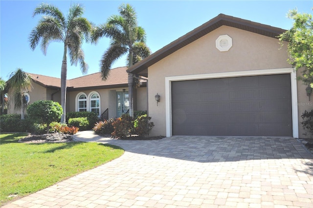 ranch-style home featuring a garage, a front lawn, decorative driveway, and stucco siding