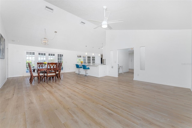 dining room featuring ceiling fan, high vaulted ceiling, visible vents, and light wood-style floors