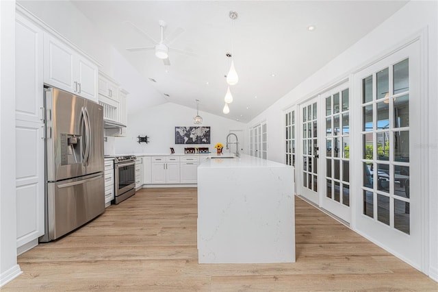 kitchen featuring appliances with stainless steel finishes, vaulted ceiling, light wood-style floors, white cabinetry, and a sink