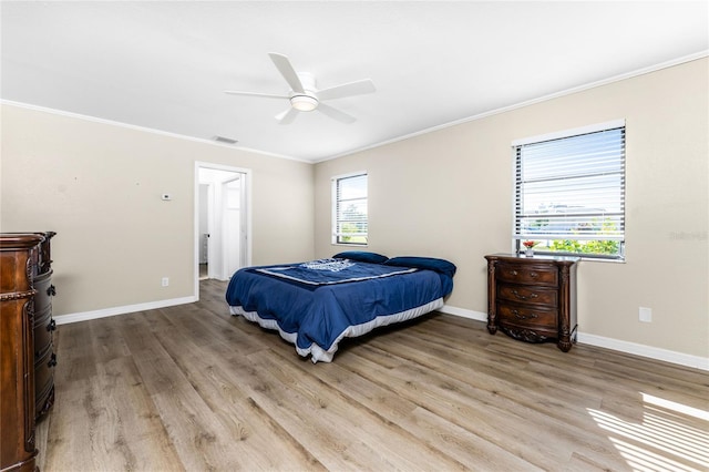 bedroom featuring light wood finished floors, baseboards, visible vents, a ceiling fan, and ornamental molding