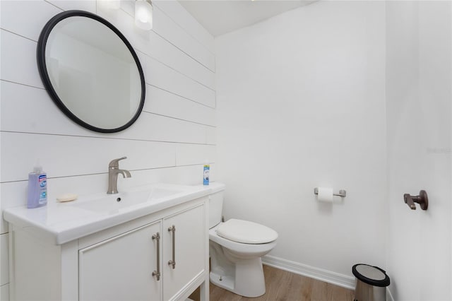 bathroom featuring toilet, wood finished floors, vanity, and baseboards