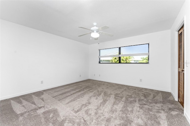 carpeted spare room featuring baseboards and a ceiling fan