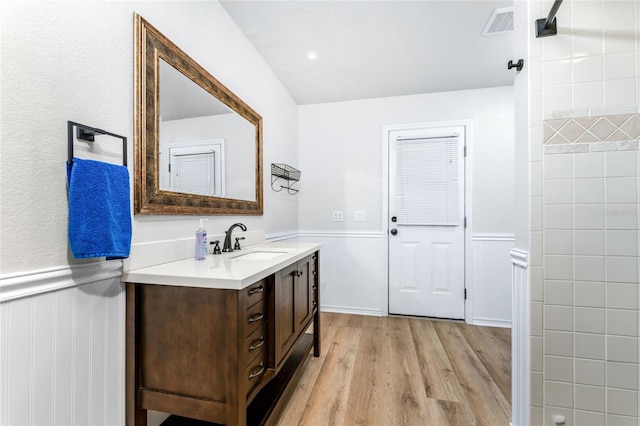 bathroom featuring visible vents, wainscoting, vanity, and wood finished floors