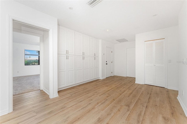 unfurnished bedroom featuring baseboards, two closets, visible vents, and light wood-style floors