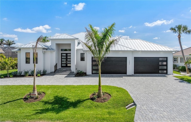 contemporary home featuring french doors, a standing seam roof, decorative driveway, and stucco siding