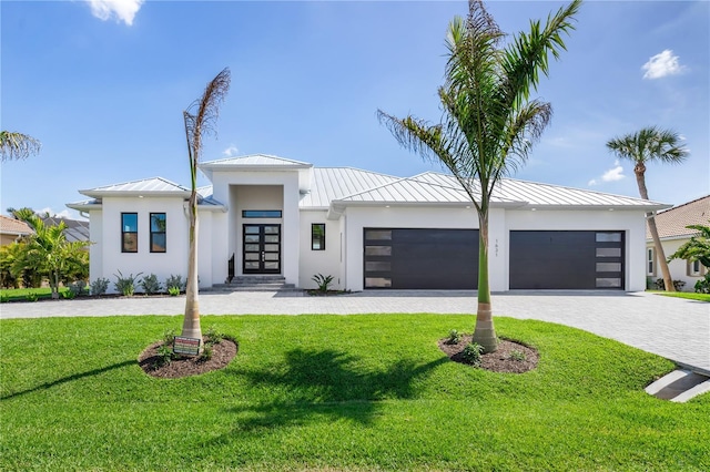 contemporary house with a garage, french doors, decorative driveway, stucco siding, and a standing seam roof