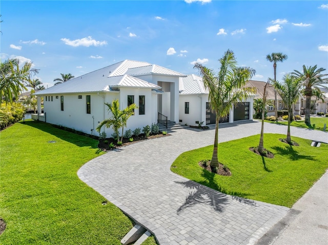 view of front of house featuring curved driveway, stucco siding, a front yard, a standing seam roof, and metal roof