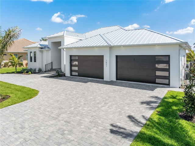 view of front facade with decorative driveway, an attached garage, and stucco siding