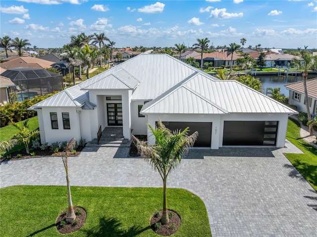 modern inspired farmhouse with french doors, decorative driveway, a standing seam roof, metal roof, and a garage