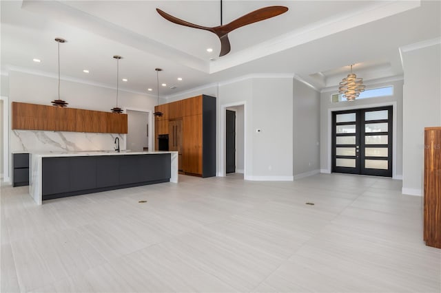 kitchen with light countertops, french doors, brown cabinets, a tray ceiling, and modern cabinets