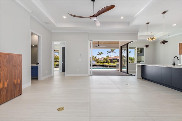 interior space with recessed lighting, a raised ceiling, a ceiling fan, a sink, and baseboards