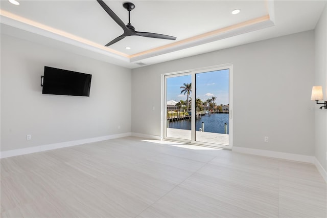 interior space with recessed lighting, a raised ceiling, a ceiling fan, and baseboards