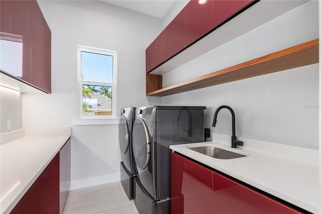 laundry room featuring baseboards, cabinet space, a sink, and washing machine and clothes dryer