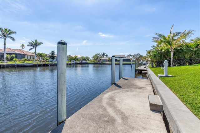 dock area with a water view, a residential view, and a lawn