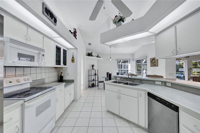 kitchen with light tile patterned floors, white appliances, a sink, white cabinets, and tasteful backsplash