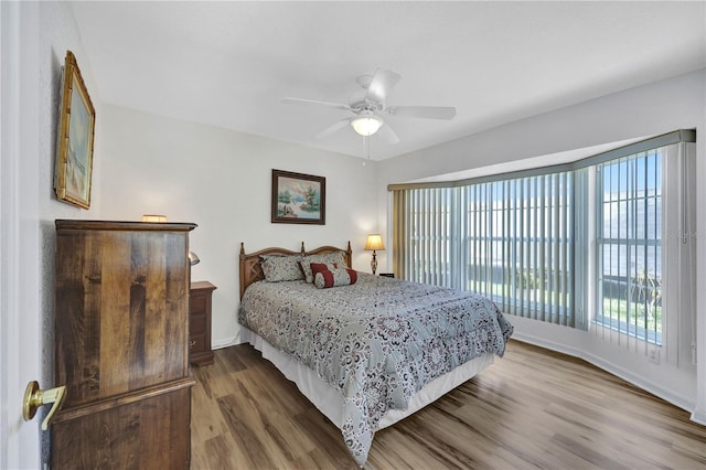 bedroom with a ceiling fan, baseboards, and wood finished floors