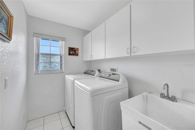 washroom with cabinet space, light tile patterned flooring, a sink, independent washer and dryer, and baseboards