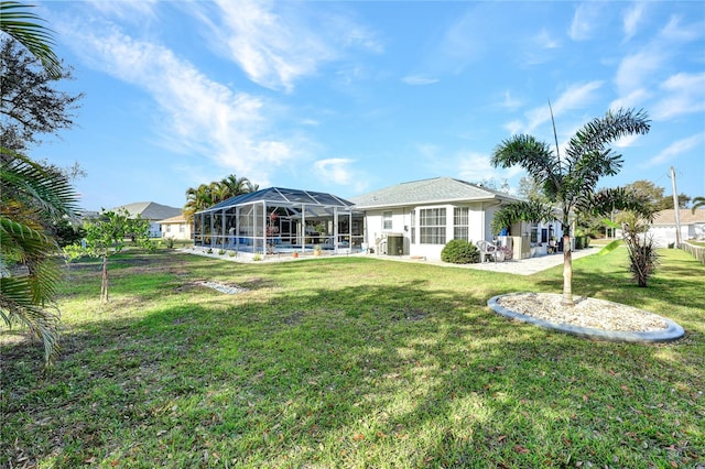 rear view of house featuring a lanai, central AC unit, and a lawn