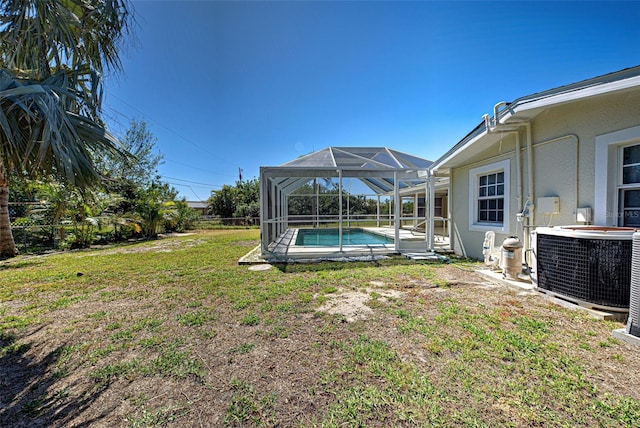 view of yard featuring glass enclosure, an outdoor pool, and central AC