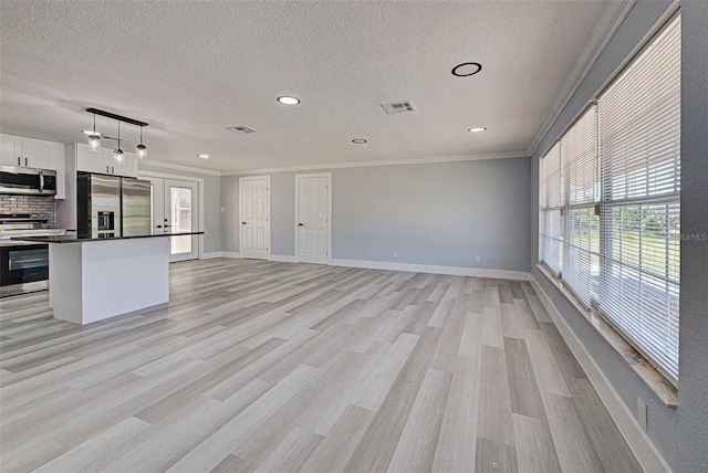 kitchen with visible vents, light wood finished floors, ornamental molding, stainless steel appliances, and dark countertops