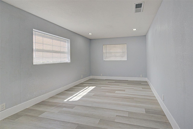 empty room with visible vents, light wood-style floors, and baseboards