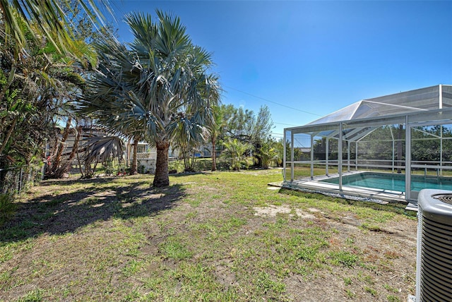 view of yard featuring glass enclosure, cooling unit, a fenced backyard, and an outdoor pool