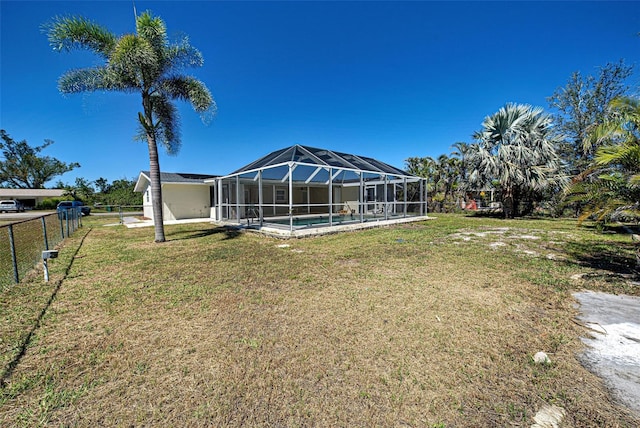 back of property featuring an outdoor pool, glass enclosure, a yard, and fence