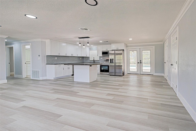 kitchen with stainless steel appliances, dark countertops, visible vents, and crown molding