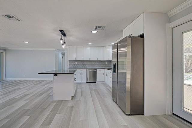 kitchen featuring stainless steel appliances, dark countertops, visible vents, and decorative backsplash