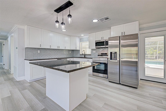 kitchen with backsplash, appliances with stainless steel finishes, and white cabinetry