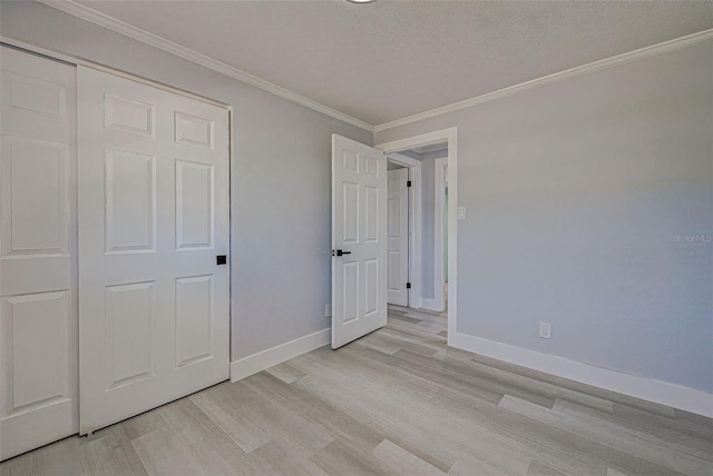 unfurnished bedroom with a textured ceiling, light wood-type flooring, baseboards, and ornamental molding