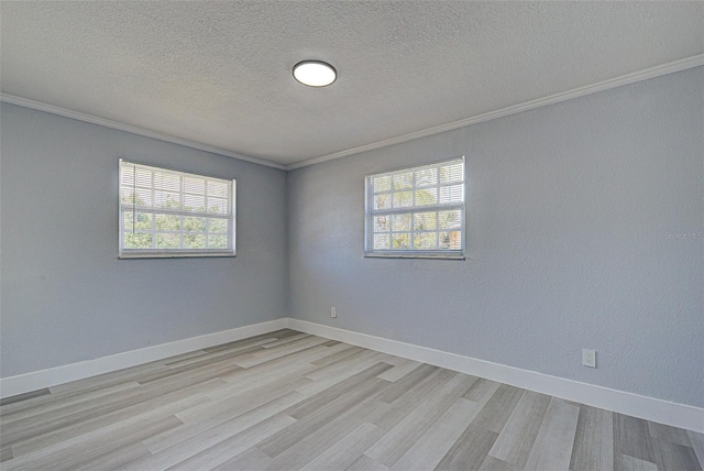 empty room with plenty of natural light, baseboards, and light wood-style floors