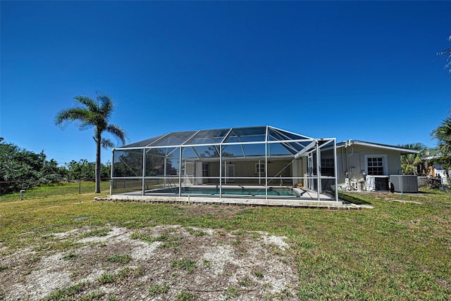 rear view of house with glass enclosure, cooling unit, a yard, an outdoor pool, and a patio area