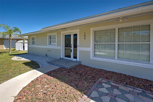 property entrance featuring stucco siding and a lawn