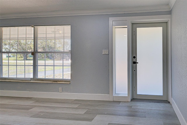 entryway with baseboards, wood finished floors, crown molding, and a textured wall