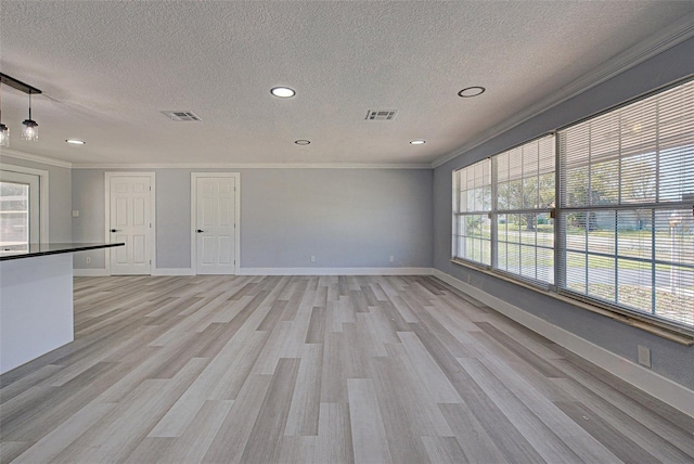 unfurnished room featuring light wood finished floors, visible vents, baseboards, and ornamental molding