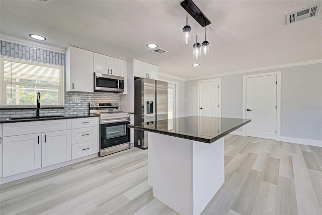 kitchen with visible vents, ornamental molding, appliances with stainless steel finishes, and a sink