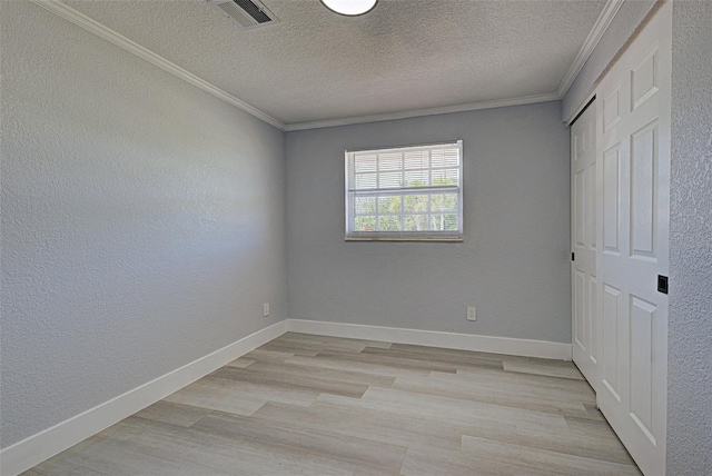 unfurnished bedroom featuring light wood finished floors, visible vents, crown molding, and baseboards