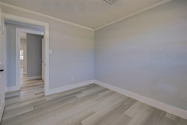 spare room featuring baseboards, a textured ceiling, light wood-style floors, and ornamental molding