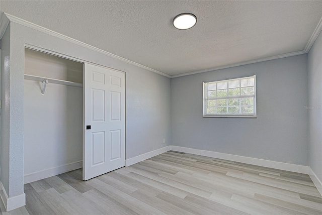 unfurnished bedroom with baseboards, light wood-style floors, ornamental molding, and a textured ceiling