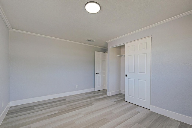 unfurnished bedroom featuring light wood finished floors, crown molding, baseboards, a closet, and a textured ceiling