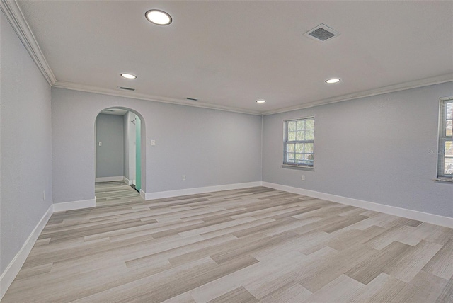 unfurnished room featuring baseboards, arched walkways, crown molding, and light wood finished floors