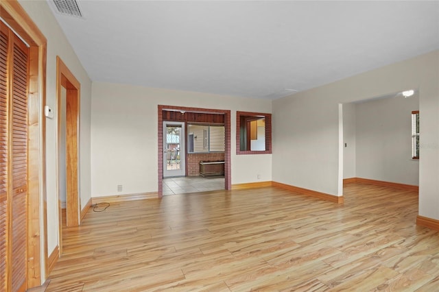 unfurnished living room featuring baseboards, visible vents, and light wood-style floors