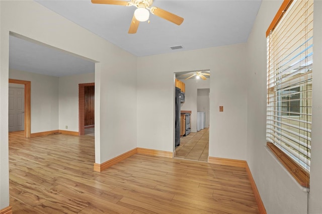 empty room with light wood-style flooring, visible vents, and baseboards